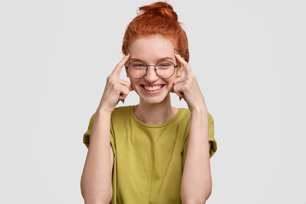 Mulher sorrindo e apontando para a própria cabeça, simbolizando os tipos de ergonomia cognitiva