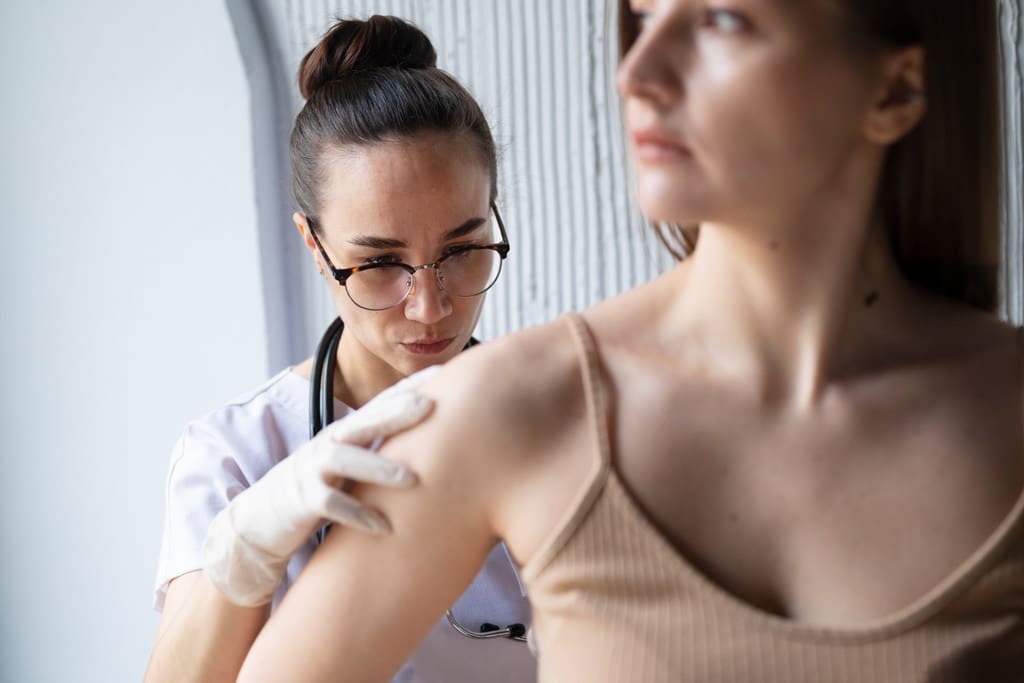 Médica examinando as costas de uma paciente, simbolizando doenças do trabalho