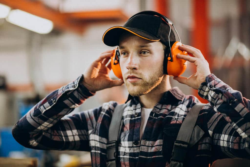 Profissional colocando protetores auriculares, simbolizando ruído ocupacional