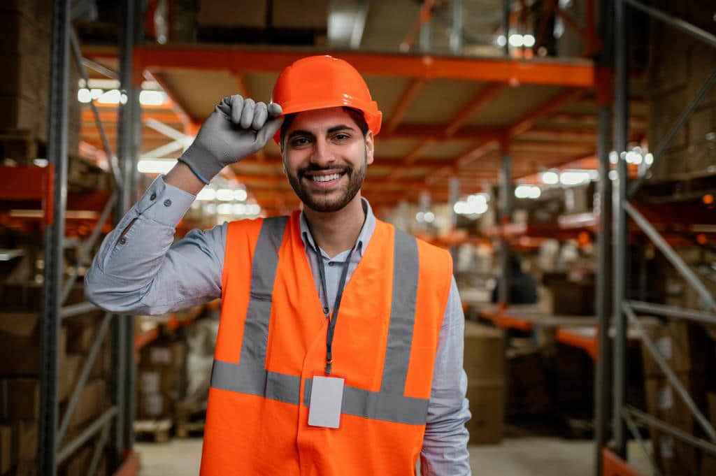 Colaborador com luvas, capacete, crachá e colete de segurança. Ele está segurando o capacete e sorrindo, simbolizando como fazer um mapa de risco